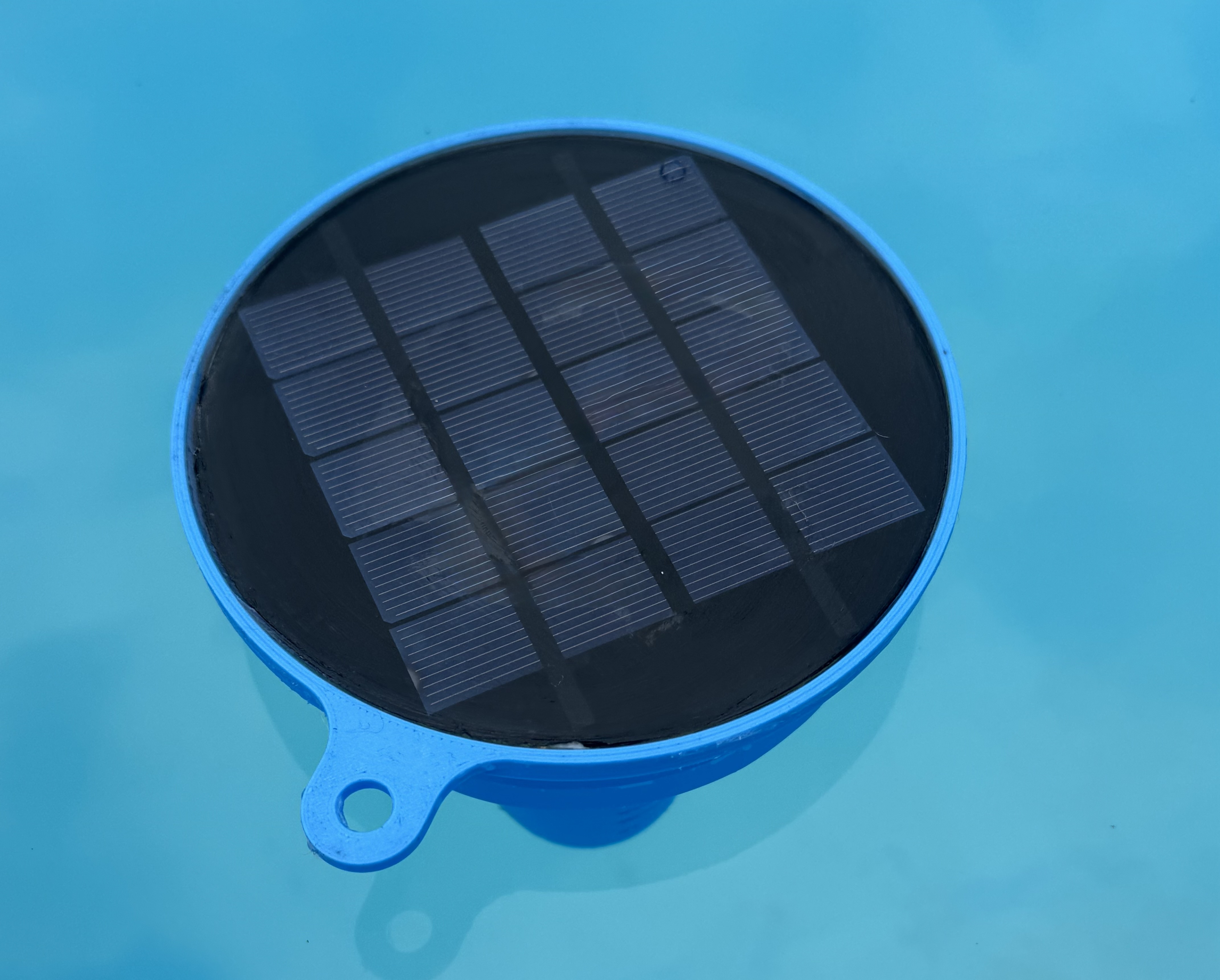 Platypus pool floatie prototype floating in pool water with solar panel visible